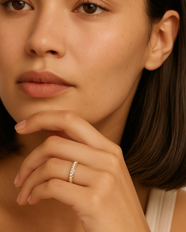 Woman with a neutral expression, wearing a ring on her finger, against a beige background