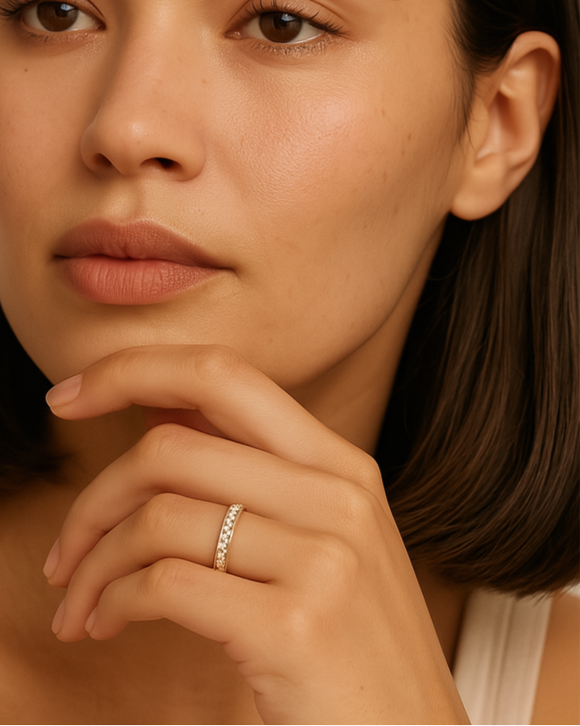 Woman with a neutral expression, wearing a ring on her finger, against a beige background