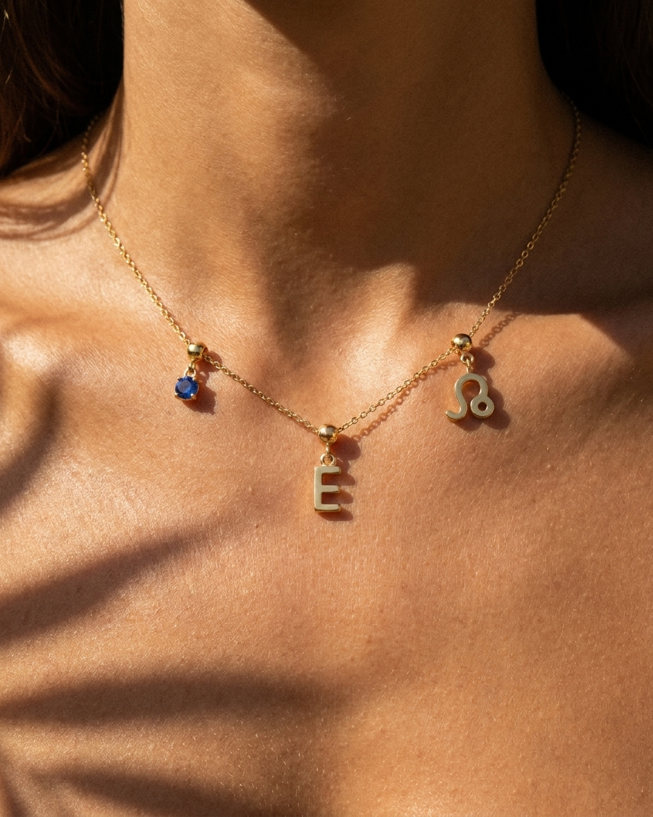 Gold initial E charm station necklace on model with Leo zodiac and sapphire
