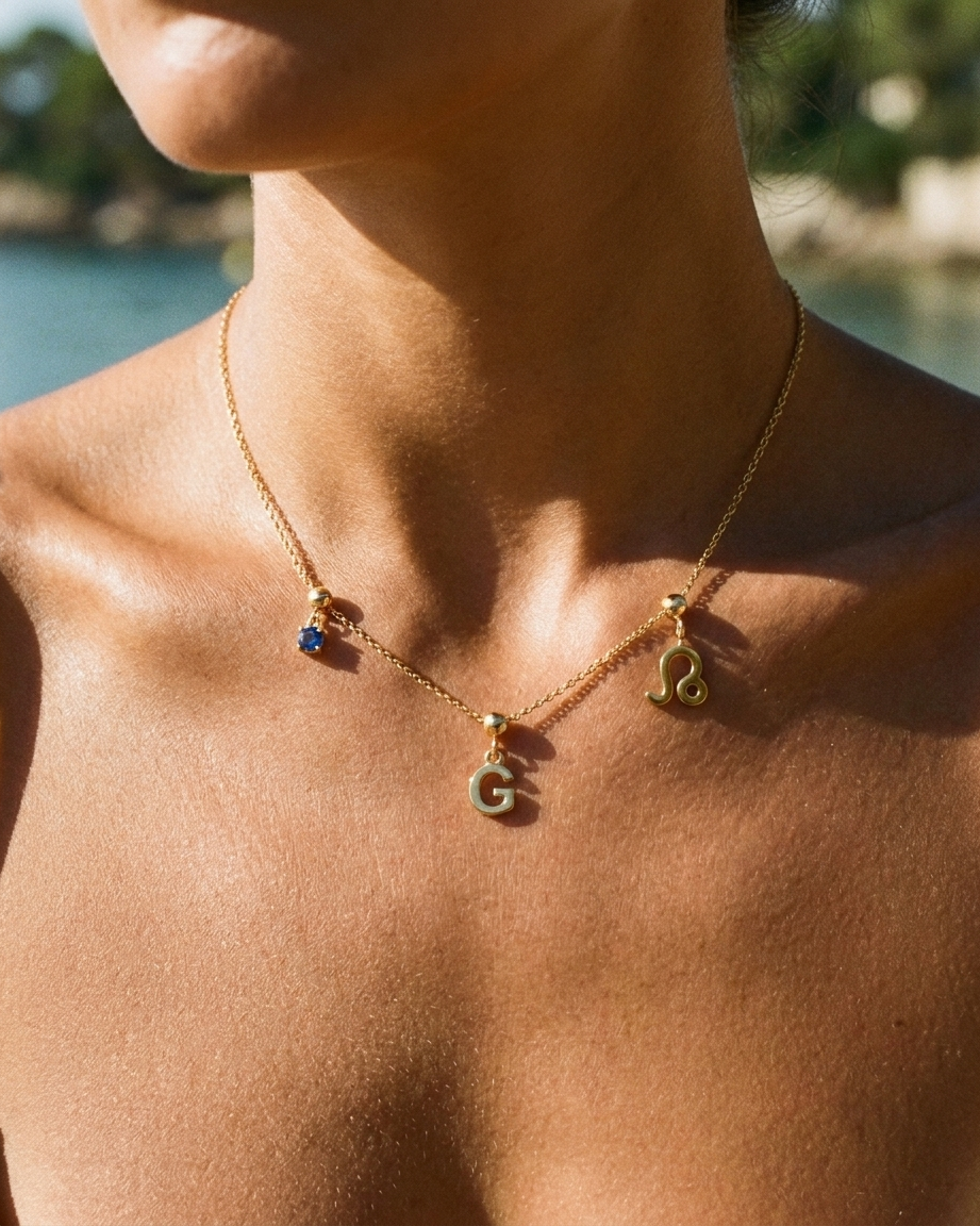 Gold initial G charm station necklace on model with Leo zodiac and sapphire
