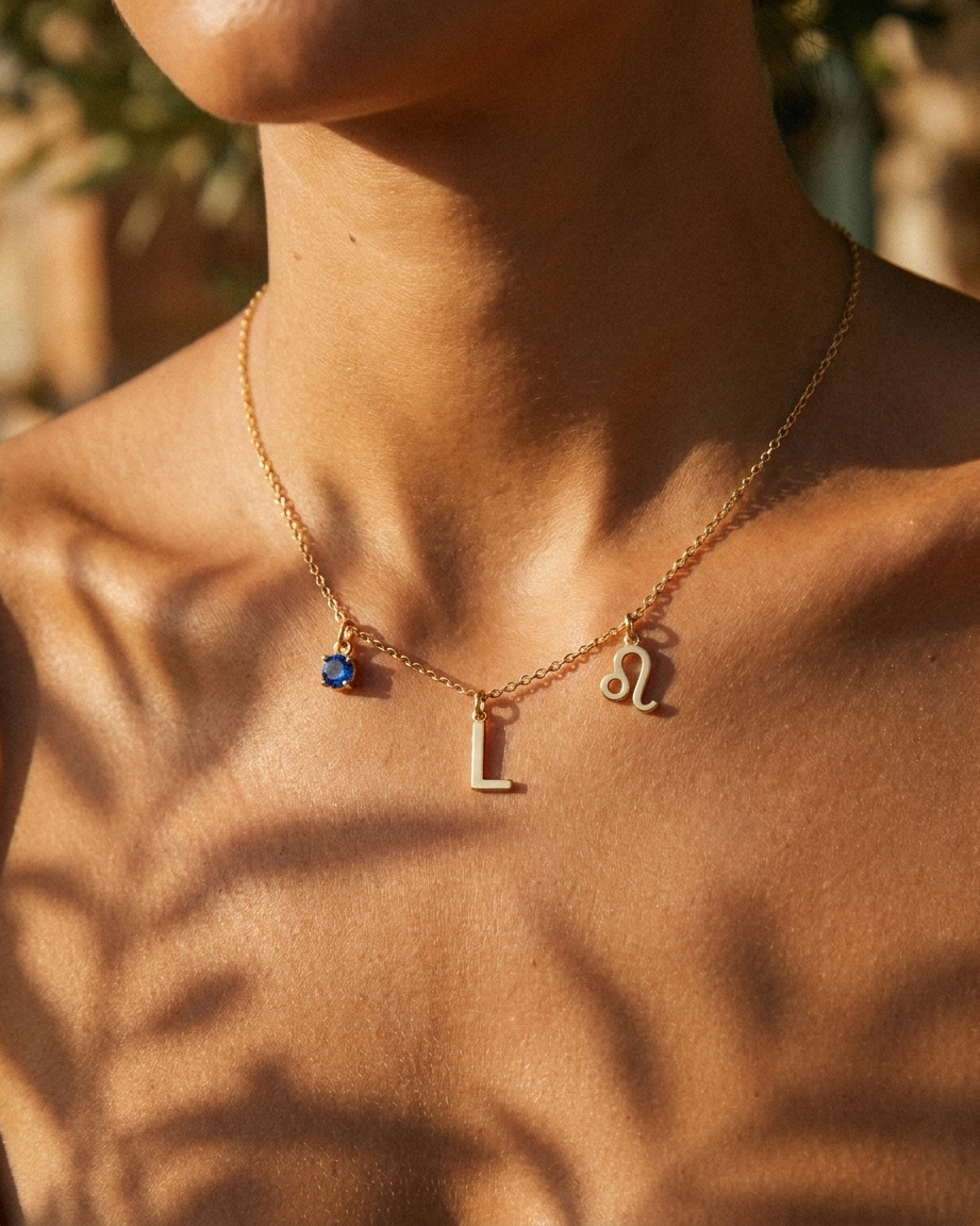 Gold initial L charm station necklace on model with Leo zodiac and sapphire