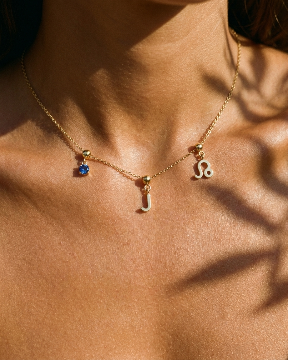 Gold initial J charm station necklace on model with Leo zodiac and sapphire