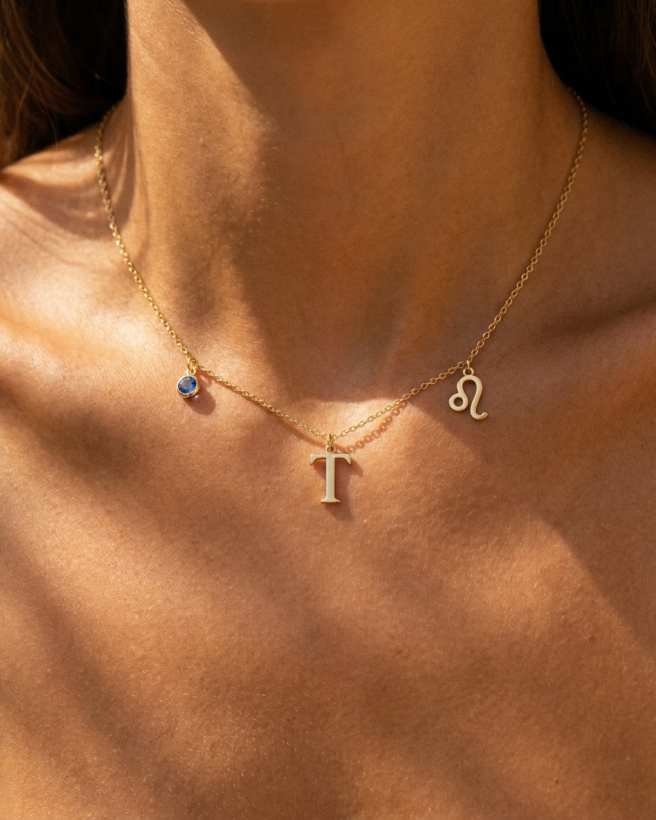Gold initial T charm station necklace on model with Leo zodiac and sapphire
