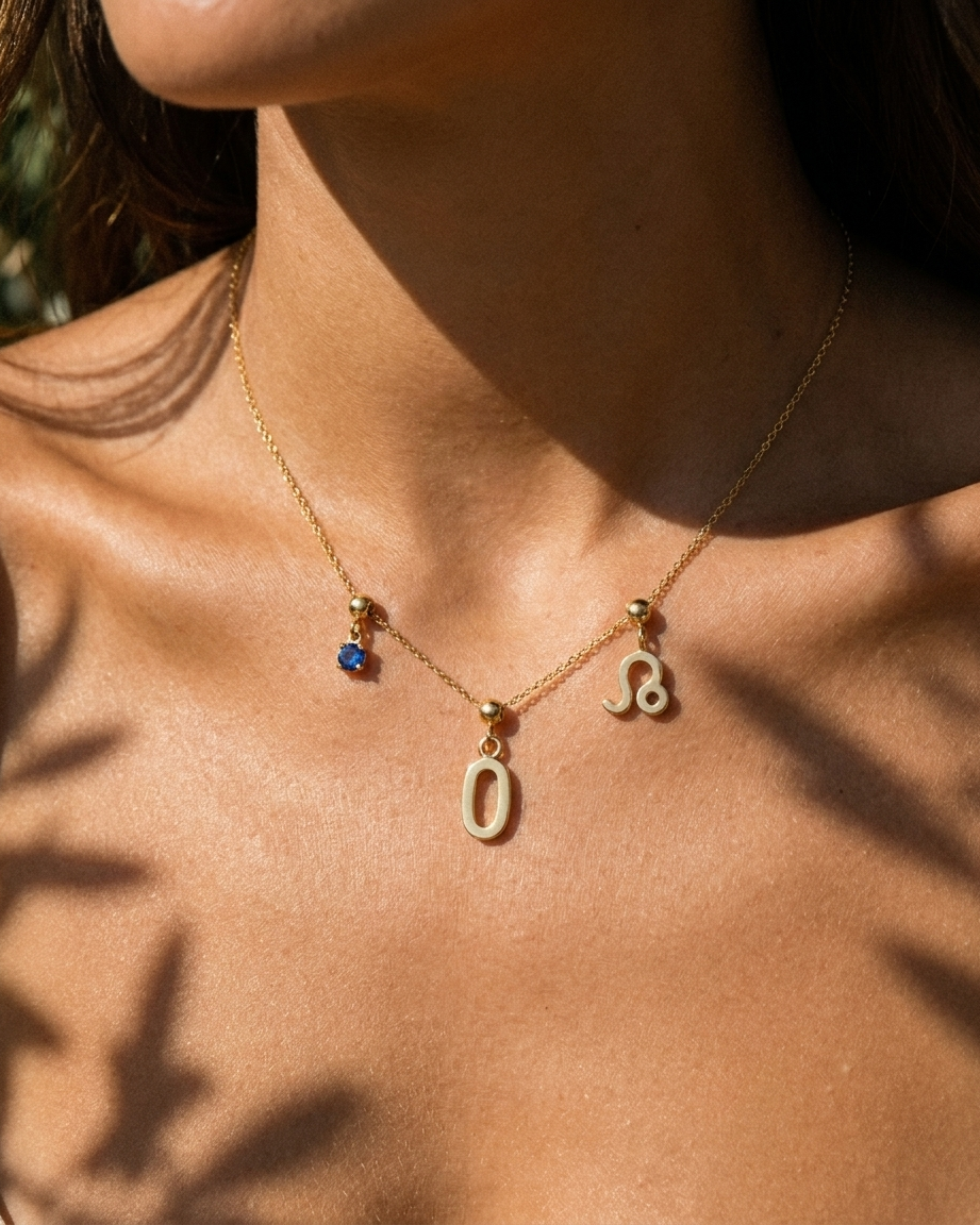 Gold number 0 charm station necklace on model with Leo zodiac and sapphire