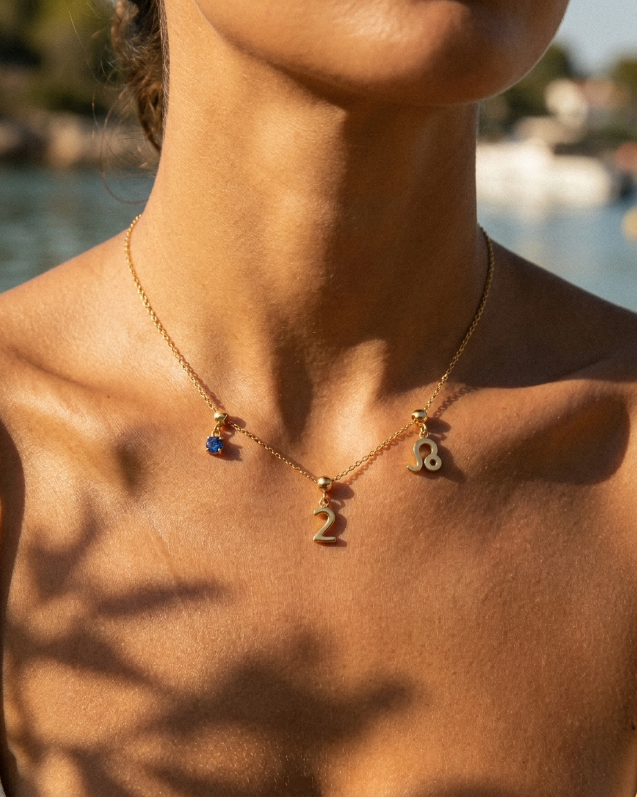 Gold number 2 charm station necklace on model with Leo zodiac and sapphire