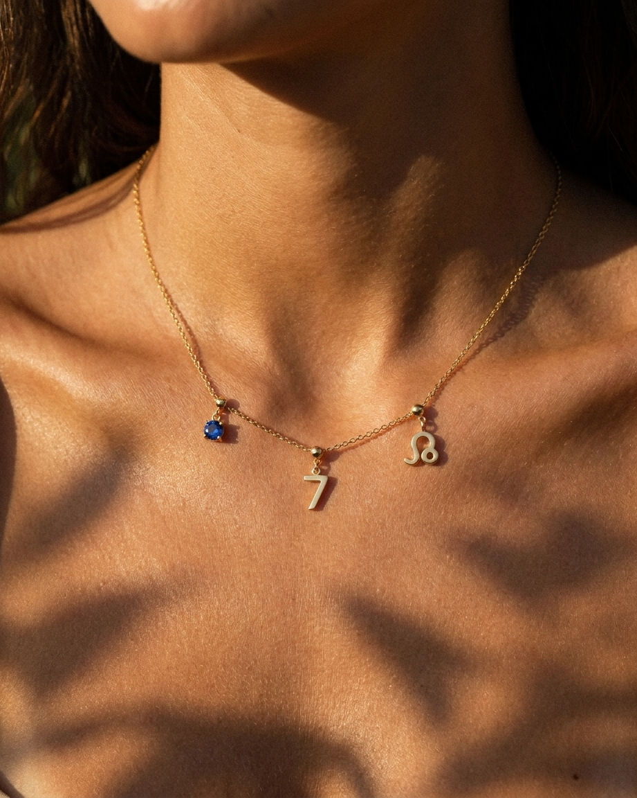 Gold number 7 charm station necklace on model with Leo zodiac and sapphire