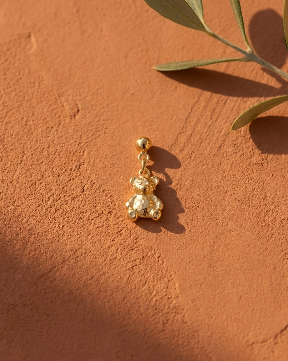 Gold bear charm flatlay, terracotta