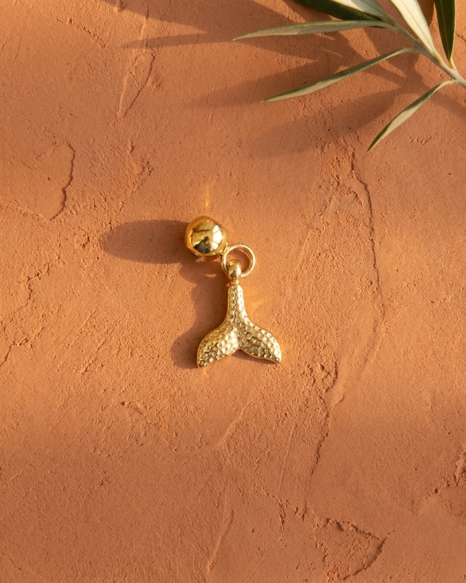 Gold mermaid tail charm flatlay, terracotta