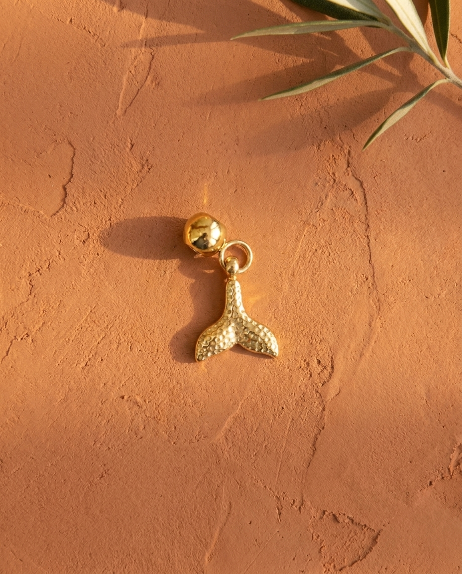 Gold mermaid tail charm flatlay, terracotta