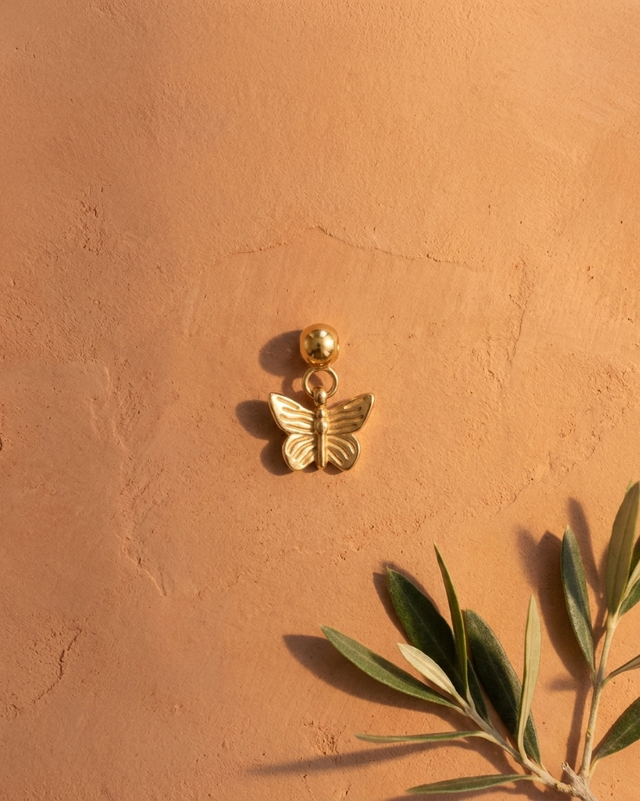 Gold butterfly charm flatlay, terracotta