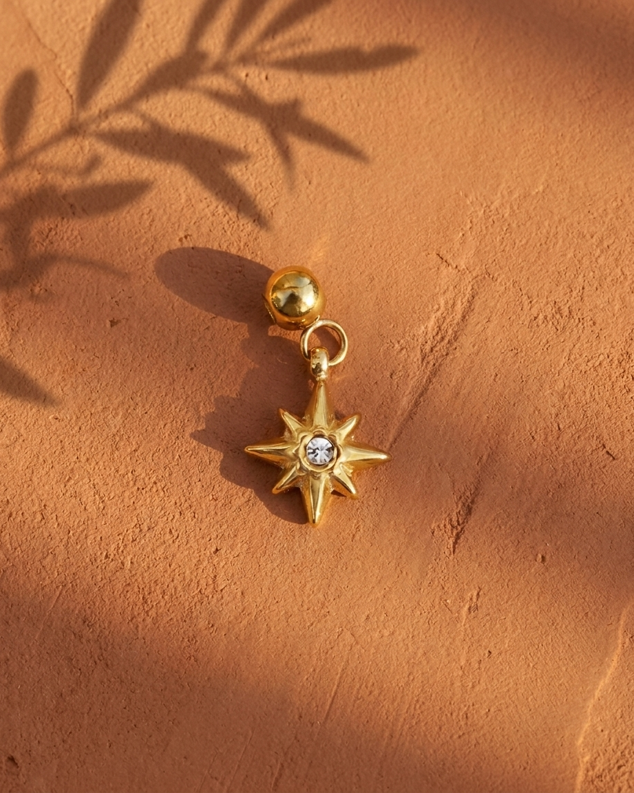 Gold compass star charm flatlay, terracotta
