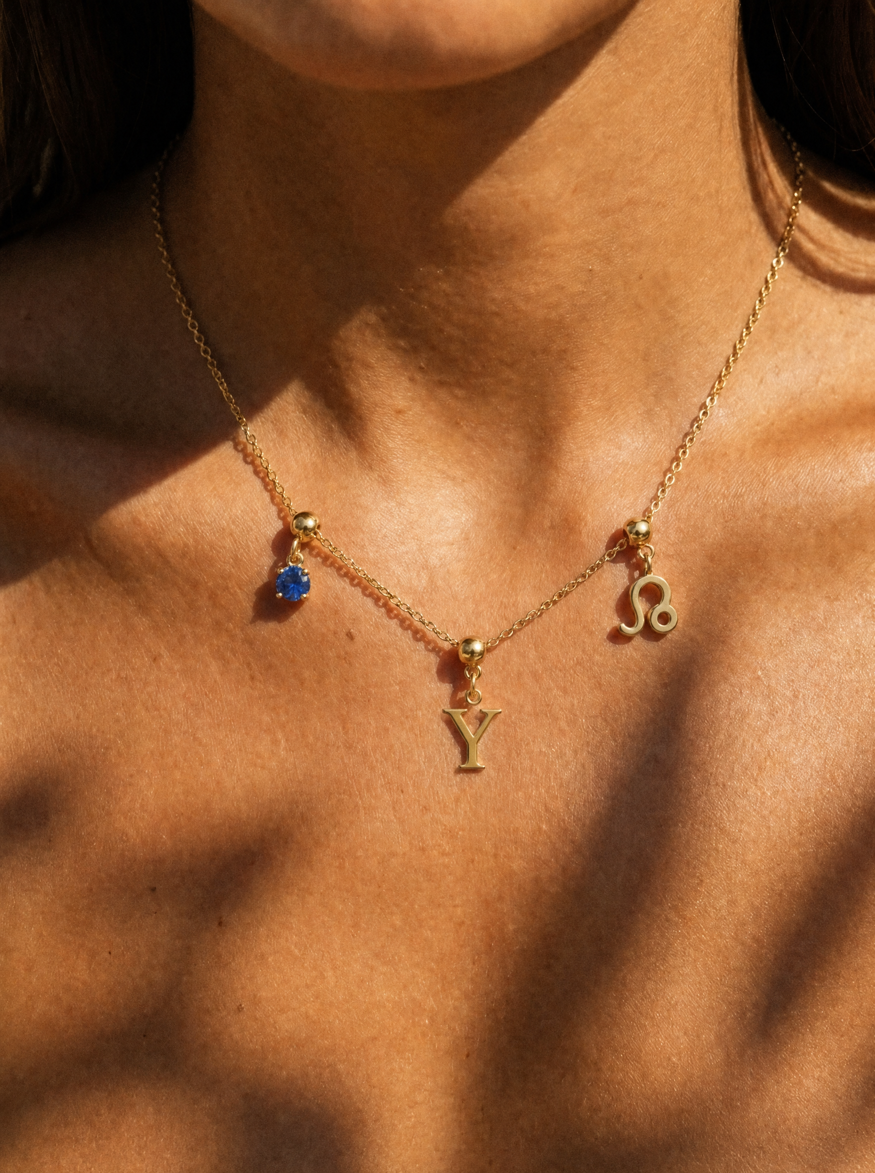 Gold initial Y charm station necklace on model with Leo zodiac and sapphire