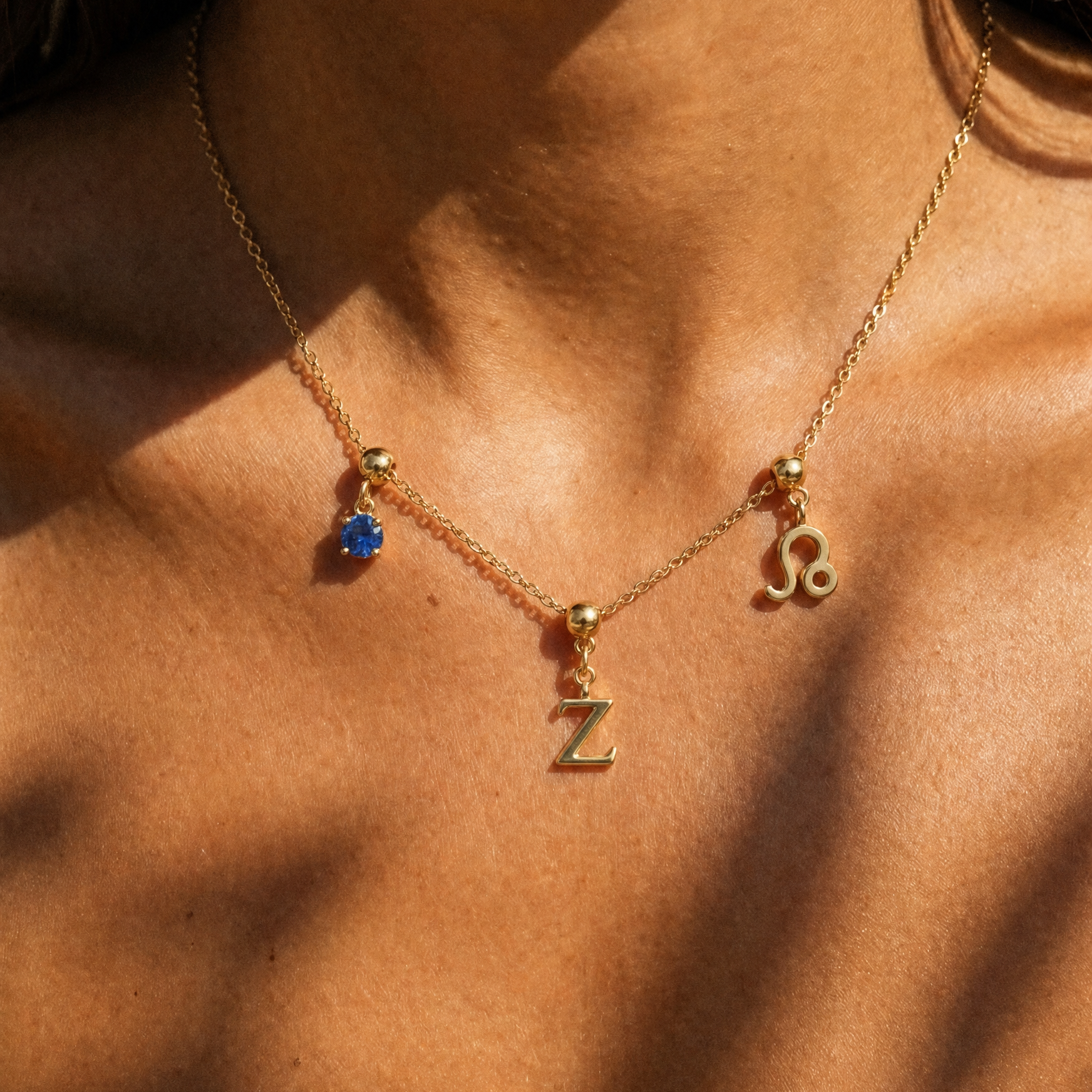 Gold initial Z charm station necklace on model with Leo zodiac and sapphire
