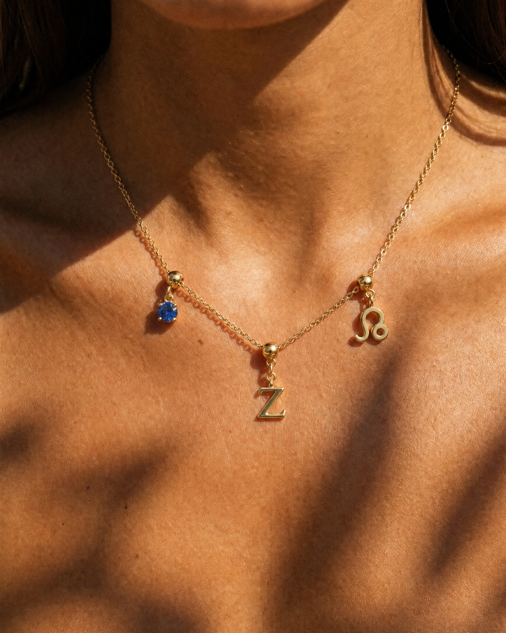 Gold initial Z charm station necklace on model with Leo zodiac and sapphire