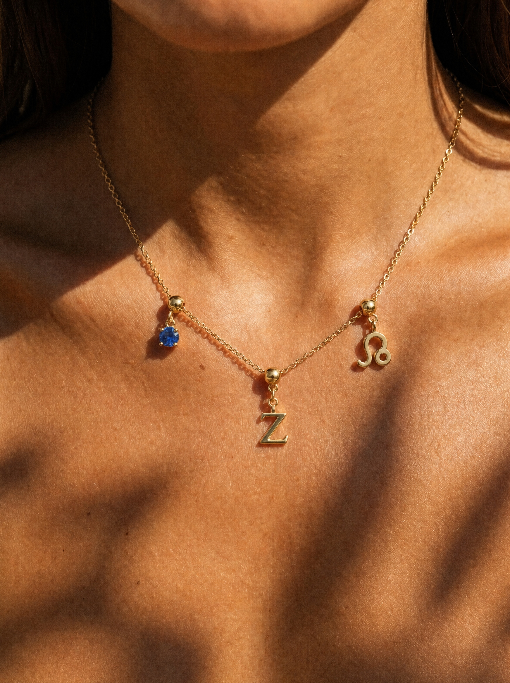 Gold initial Z charm station necklace on model with Leo zodiac and sapphire