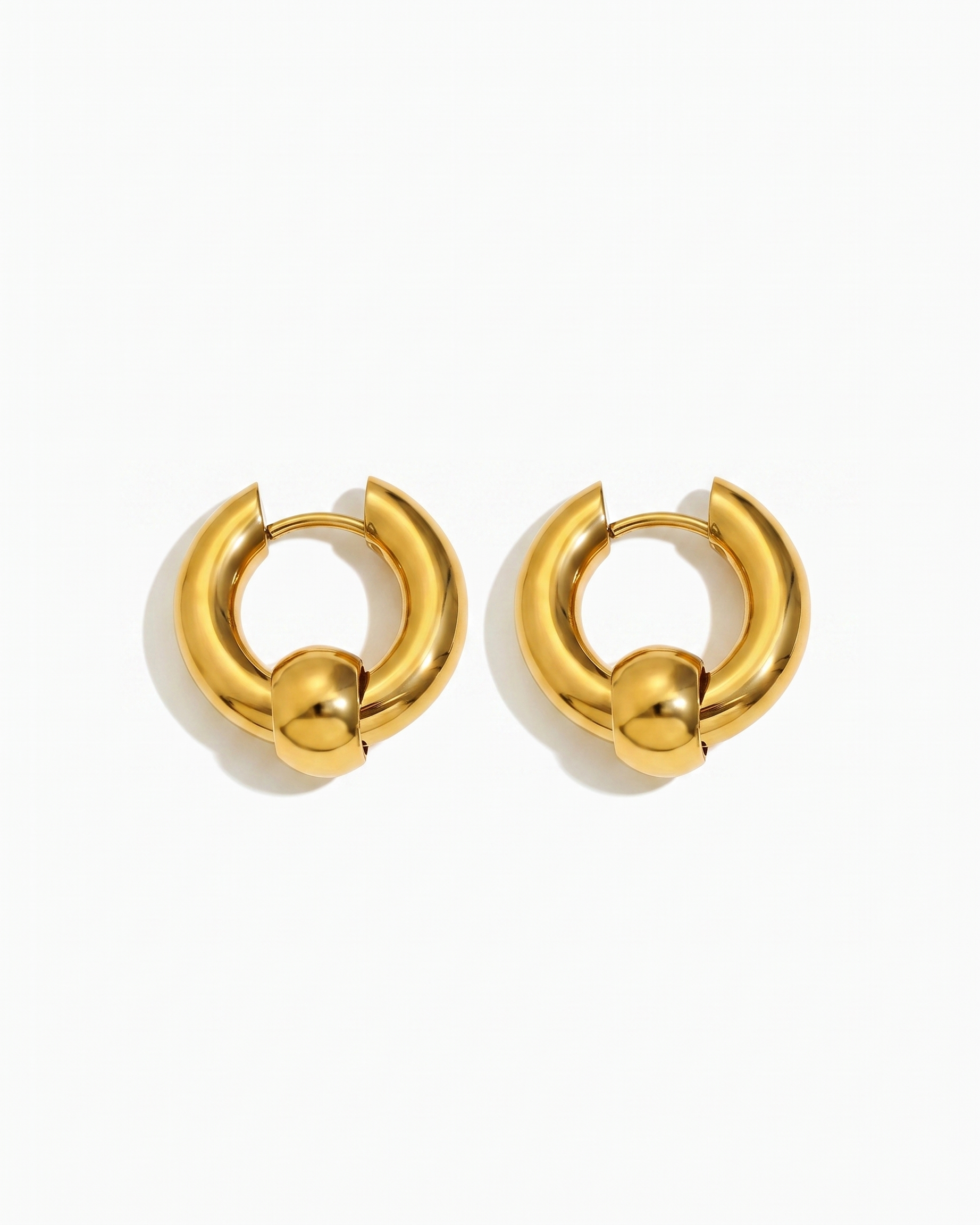 Solene chunky gold huggie hoop earrings pair on off white background