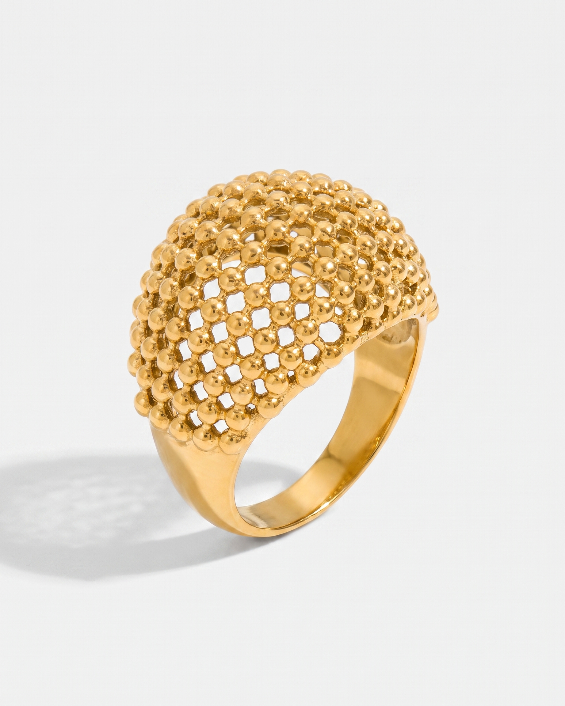 Maille openwork dome statement ring in gold on off white background
