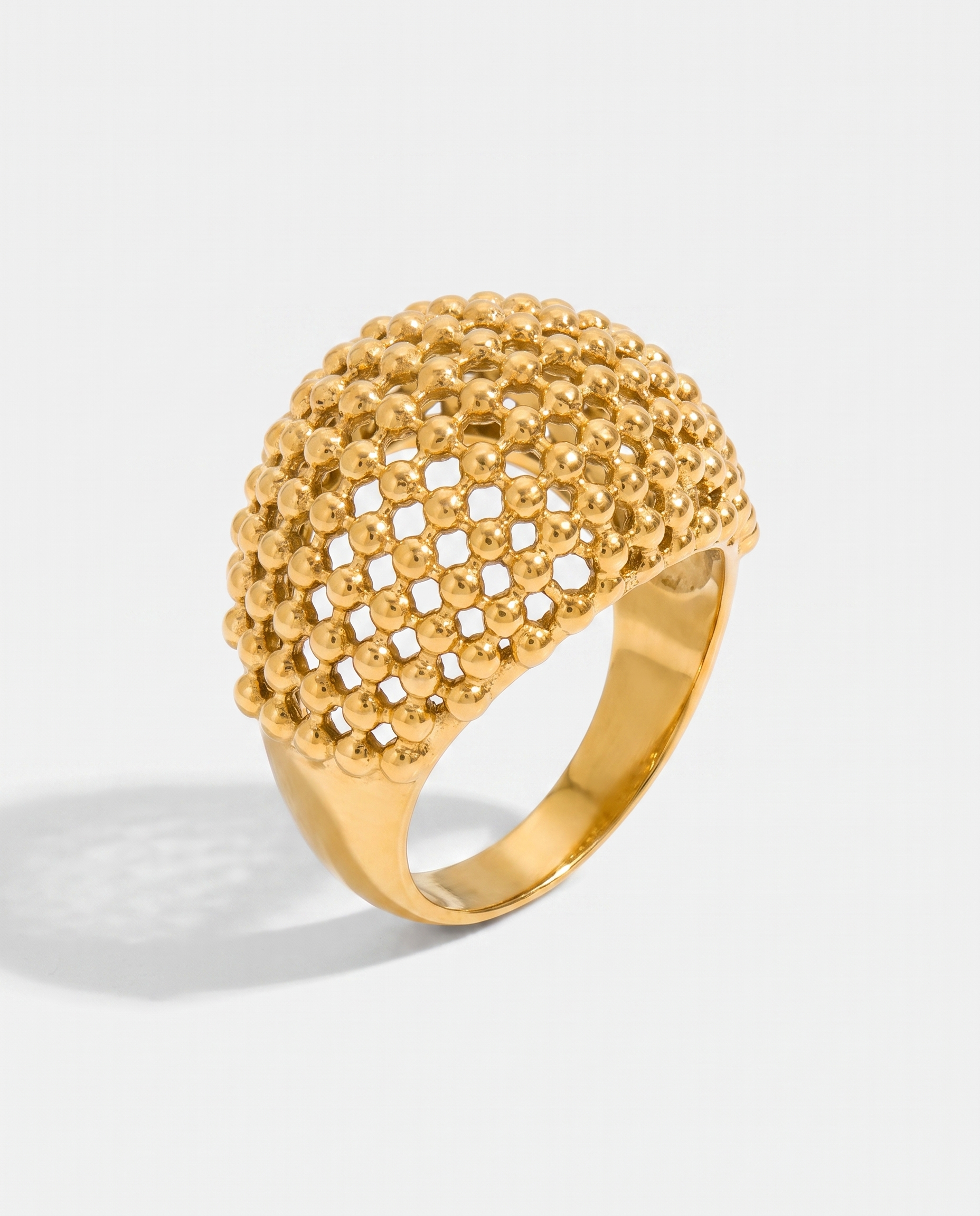 Maille openwork dome statement ring in gold on off white background