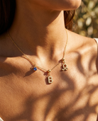 Gold initial B charm station necklace on model with Leo zodiac and sapphire