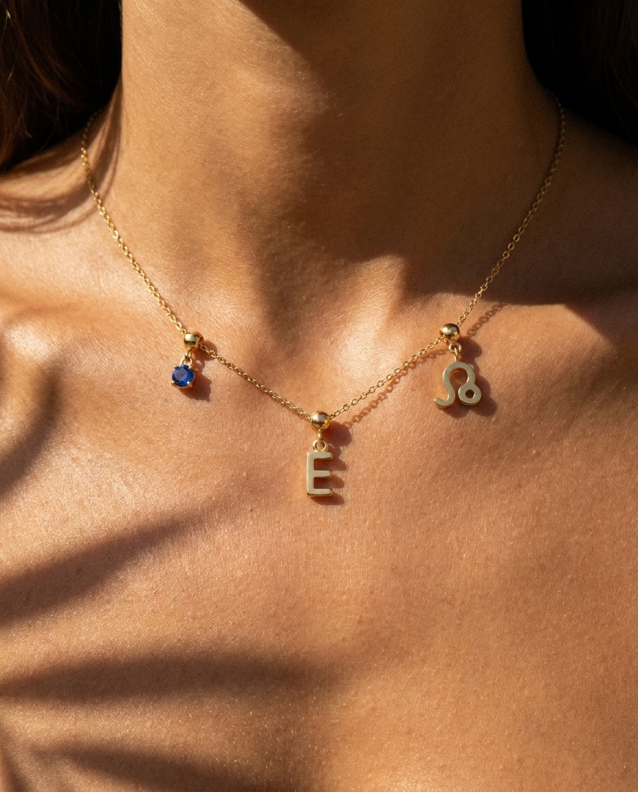 Gold initial E charm station necklace on model with Leo zodiac and sapphire