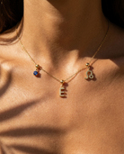 Gold initial E charm station necklace on model with Leo zodiac and sapphire