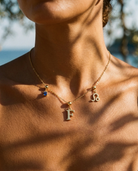 Gold initial F charm station necklace on model with Leo zodiac and sapphire
