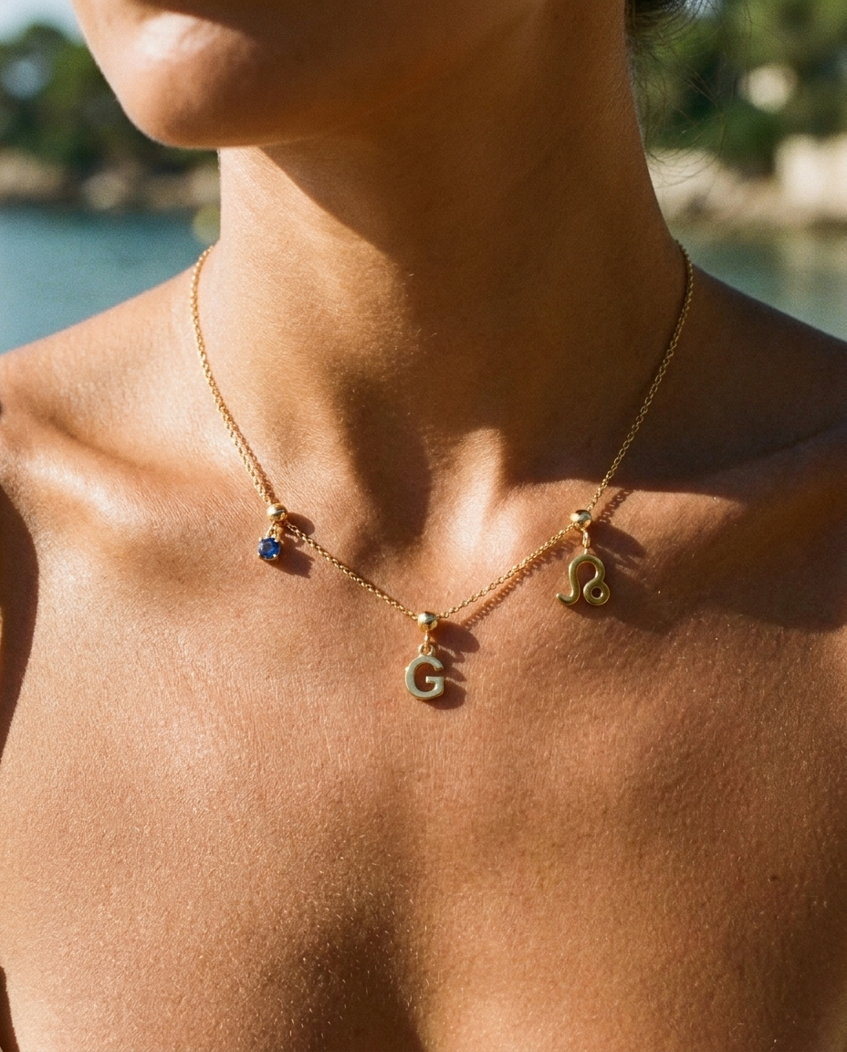 Gold initial G charm station necklace on model with Leo zodiac and sapphire