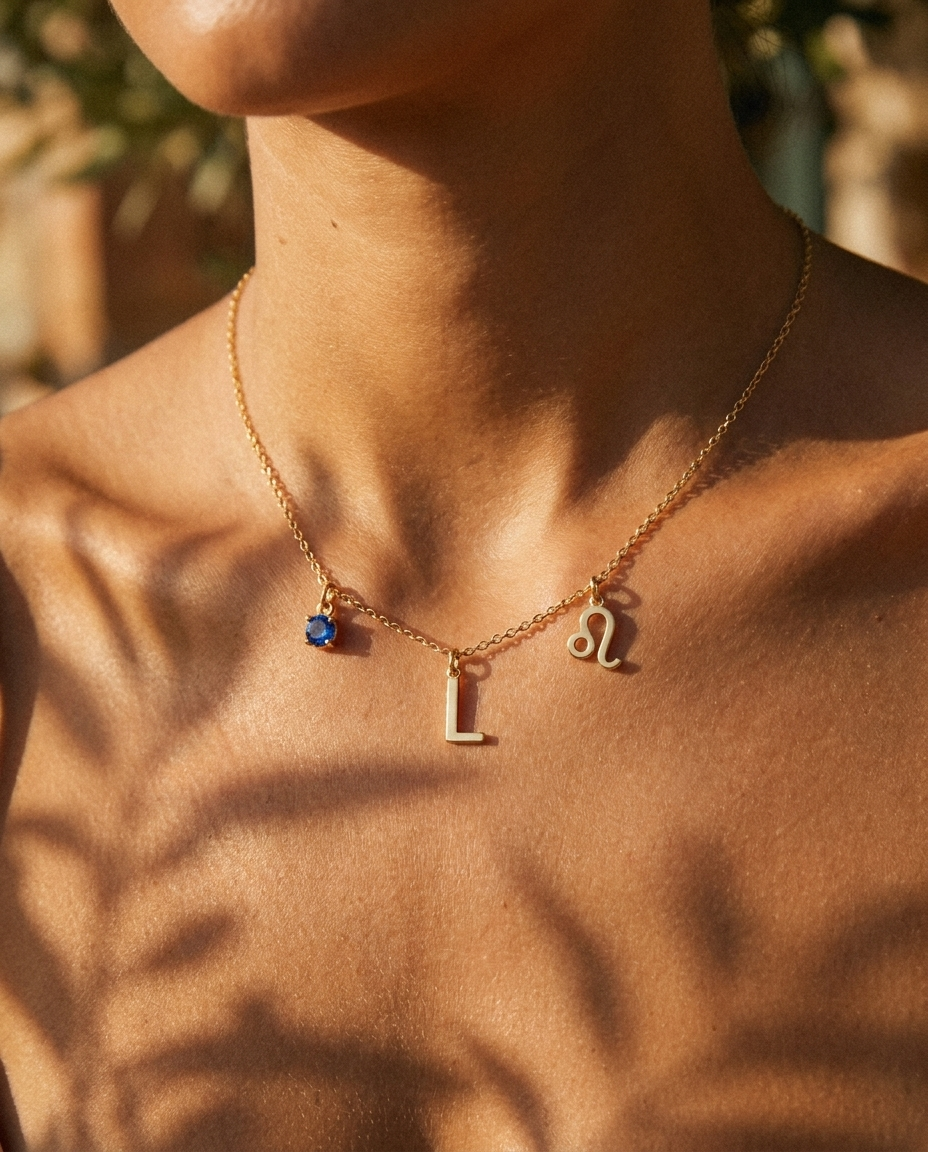 Gold initial L charm station necklace on model with Leo zodiac and sapphire