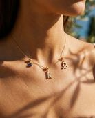 Gold initial K charm station necklace on model with Leo zodiac and sapphire