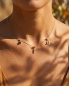 Gold initial P charm station necklace on model with Leo zodiac and sapphire
