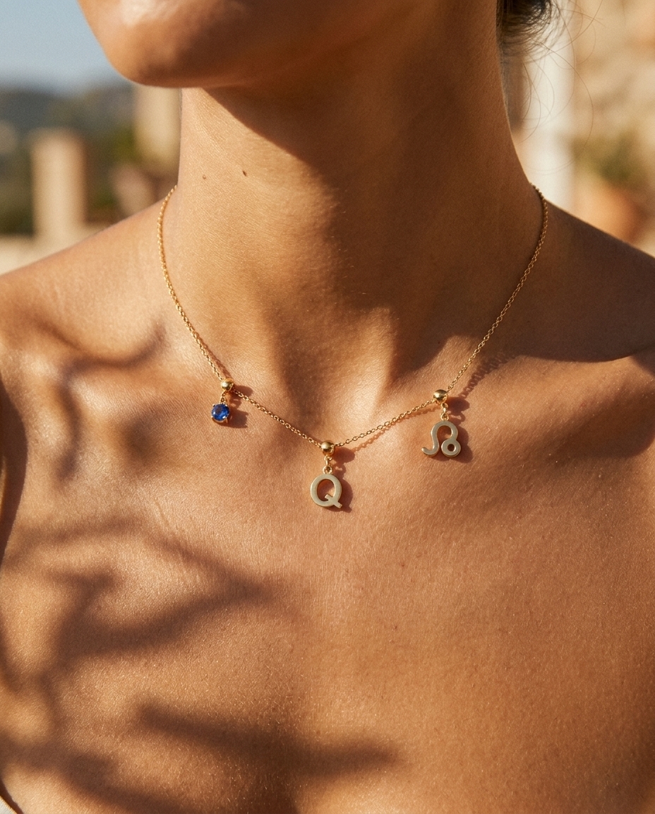 Gold initial Q charm station necklace on model with Leo zodiac and sapphire