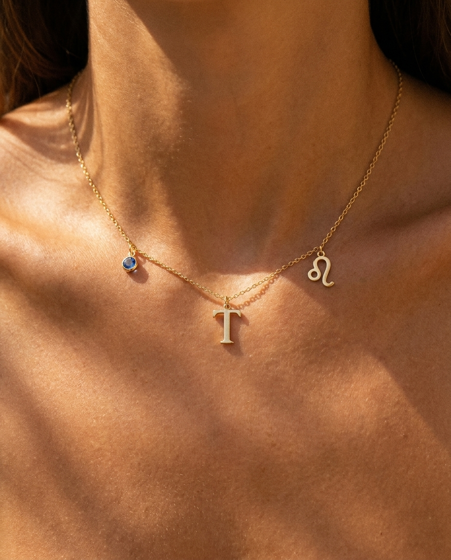 Gold initial T charm station necklace on model with Leo zodiac and sapphire