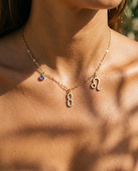 Gold number 8 charm station necklace on model with Leo zodiac and sapphire