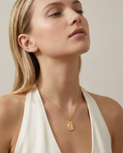 Woman wearing gold zodiac Gemini pendant necklace, neckline