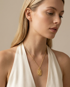 Woman wearing gold zodiac Leo pendant necklace, neckline