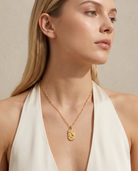 Woman wearing gold zodiac Aquarius pendant necklace, neckline