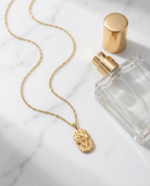 Gold zodiac Gemini pendant necklace flatlay, marble
