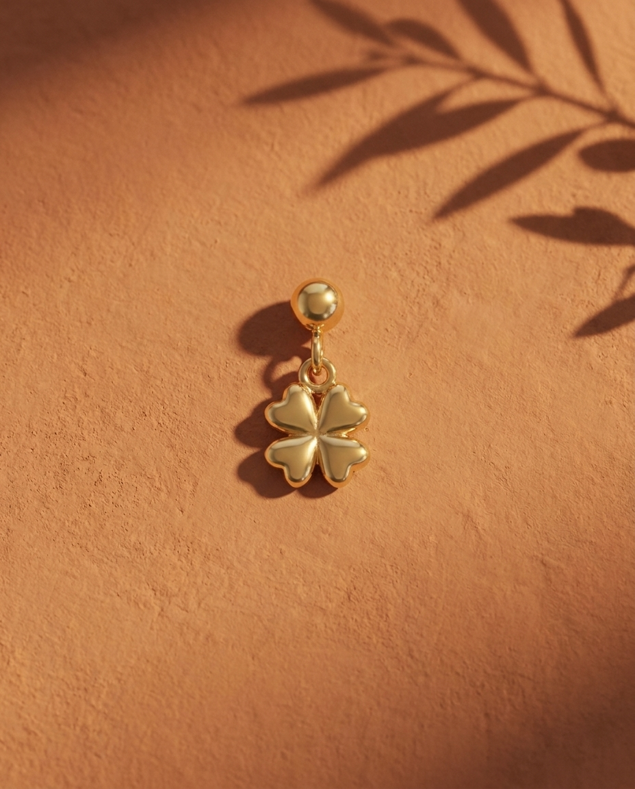 Gold four-leaf clover charm flatlay, terracotta
