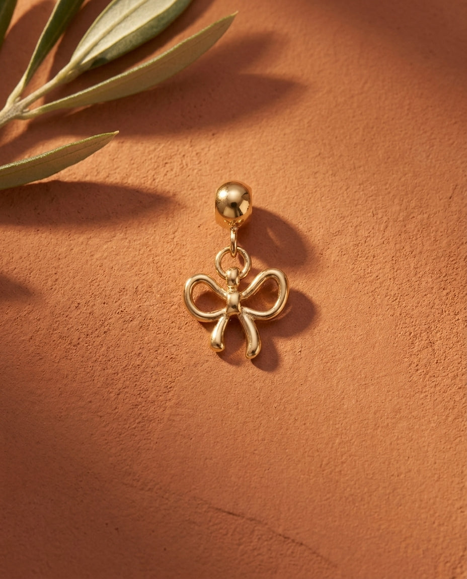 Gold bow charm flatlay, terracotta