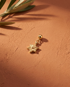 Gold sunburst star charm flatlay, terracotta