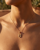 Taurus gold zodiac charm on a fine gold chain necklace, worn