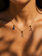 Gold initial R charm station necklace on model with Leo zodiac and sapphire