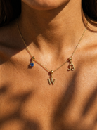 Gold initial W charm station necklace on model with Leo zodiac and sapphire
