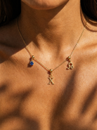 Gold initial X charm station necklace on model with Leo zodiac and sapphire