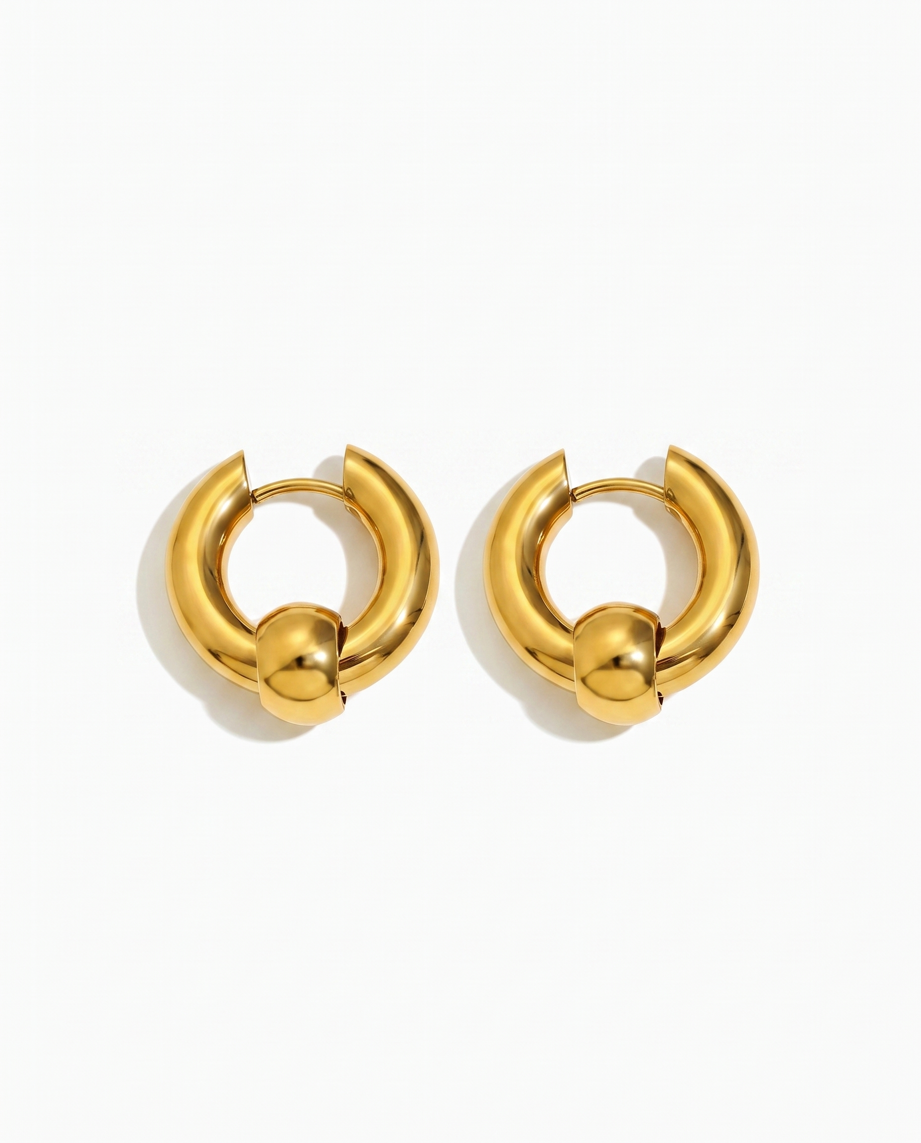 Solene chunky gold huggie hoop earrings pair on off white background