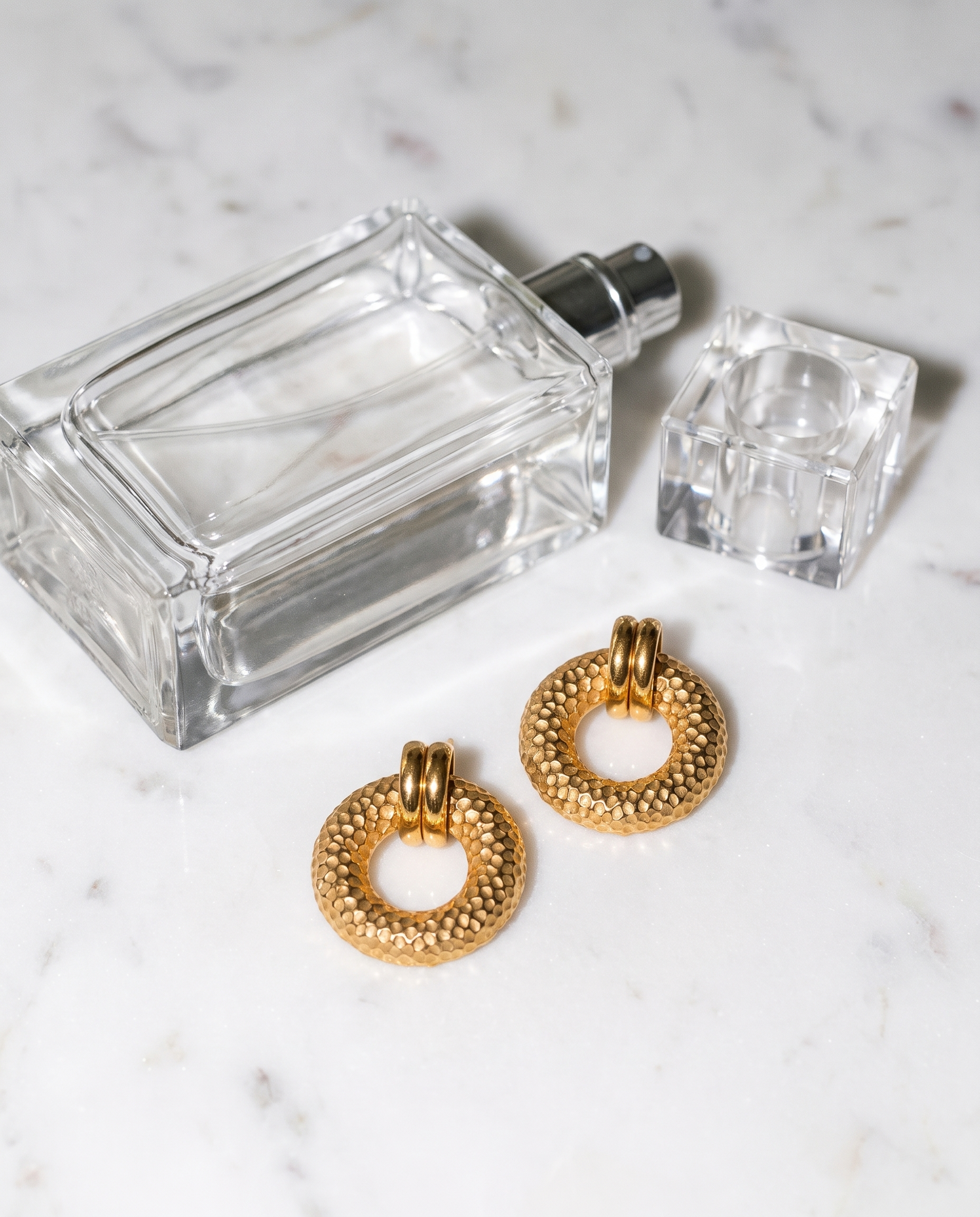 Cleo hammered gold disc earrings flatlay on marble