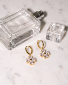 Trefle gold clover earrings flatlay on marble