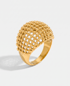 Maille openwork dome statement ring in gold on off white background