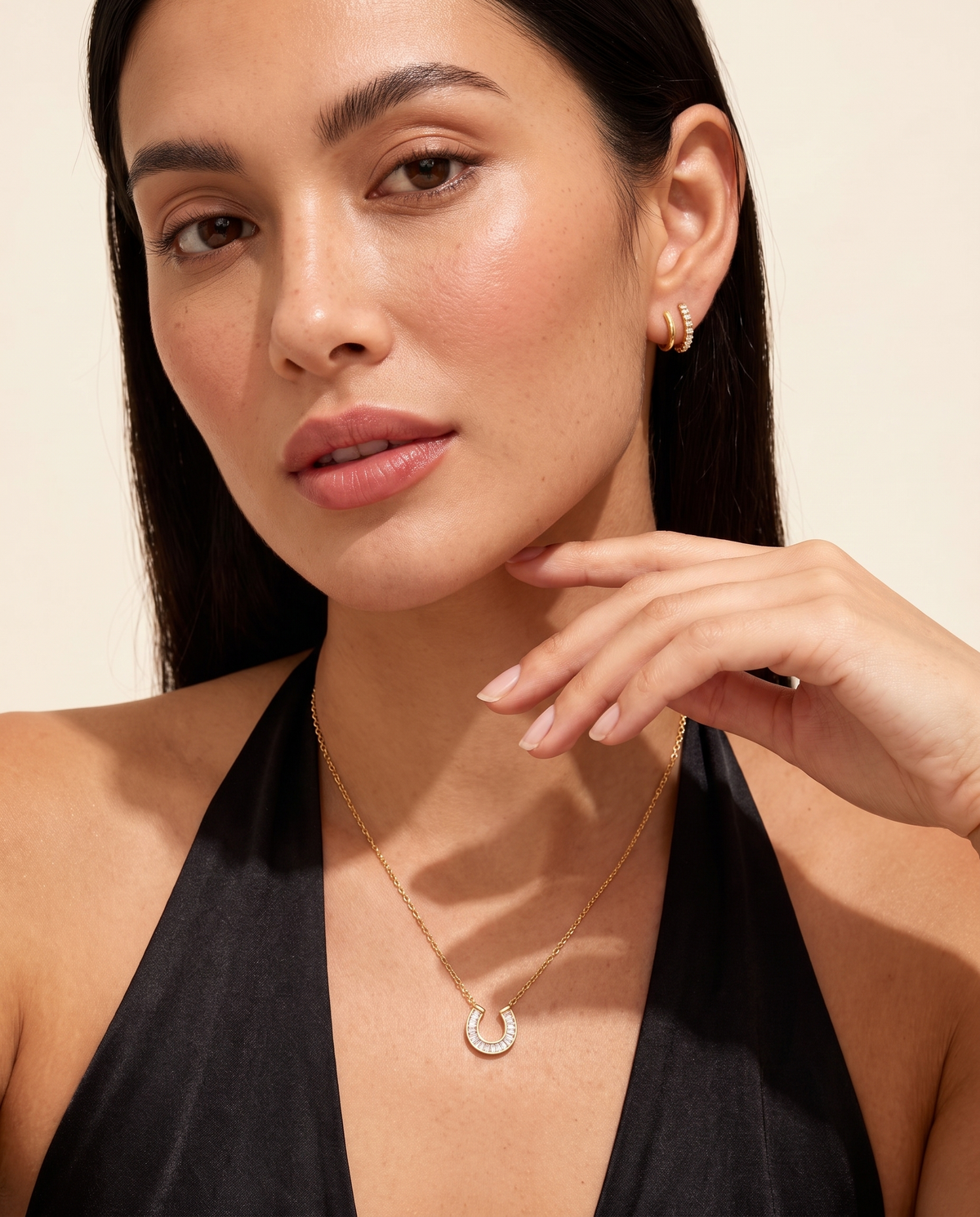 Lucky horseshoe necklace worn on model hand to collarbone