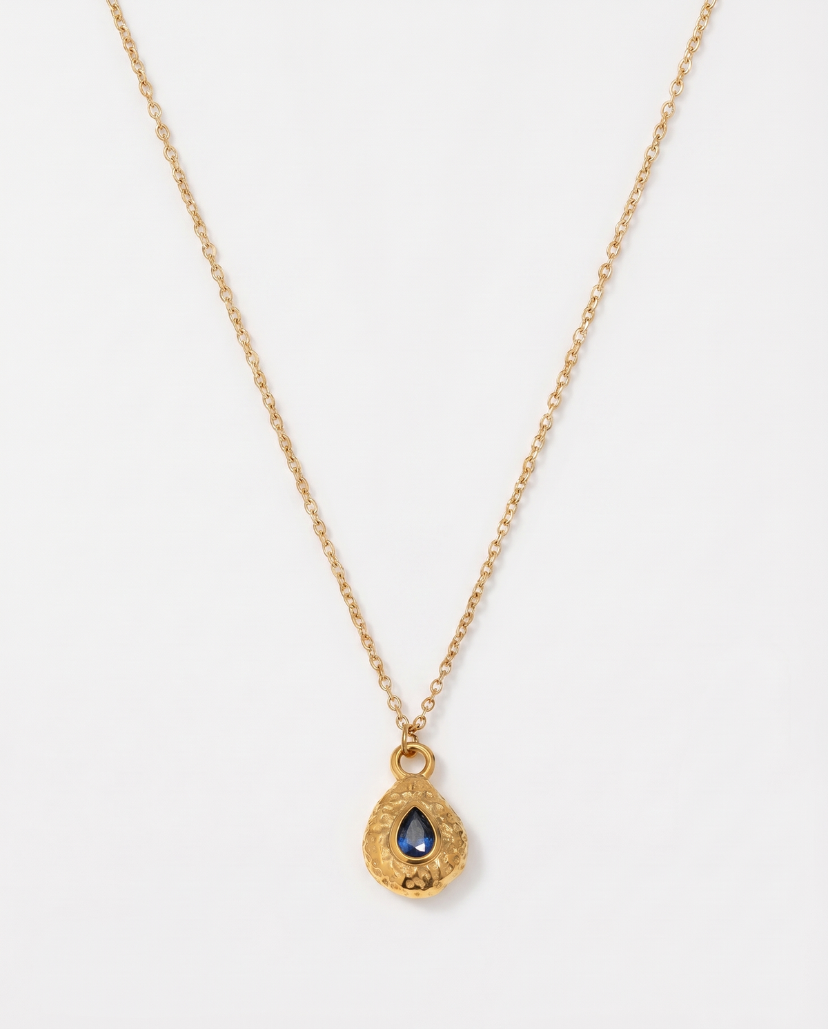 Birthstone necklace September blue teardrop gold pendant on soft studio background